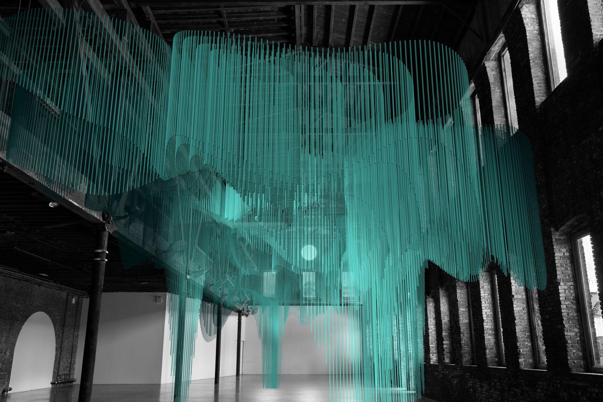 A vast bright turquoise digital architecture fills an industrial looking space.