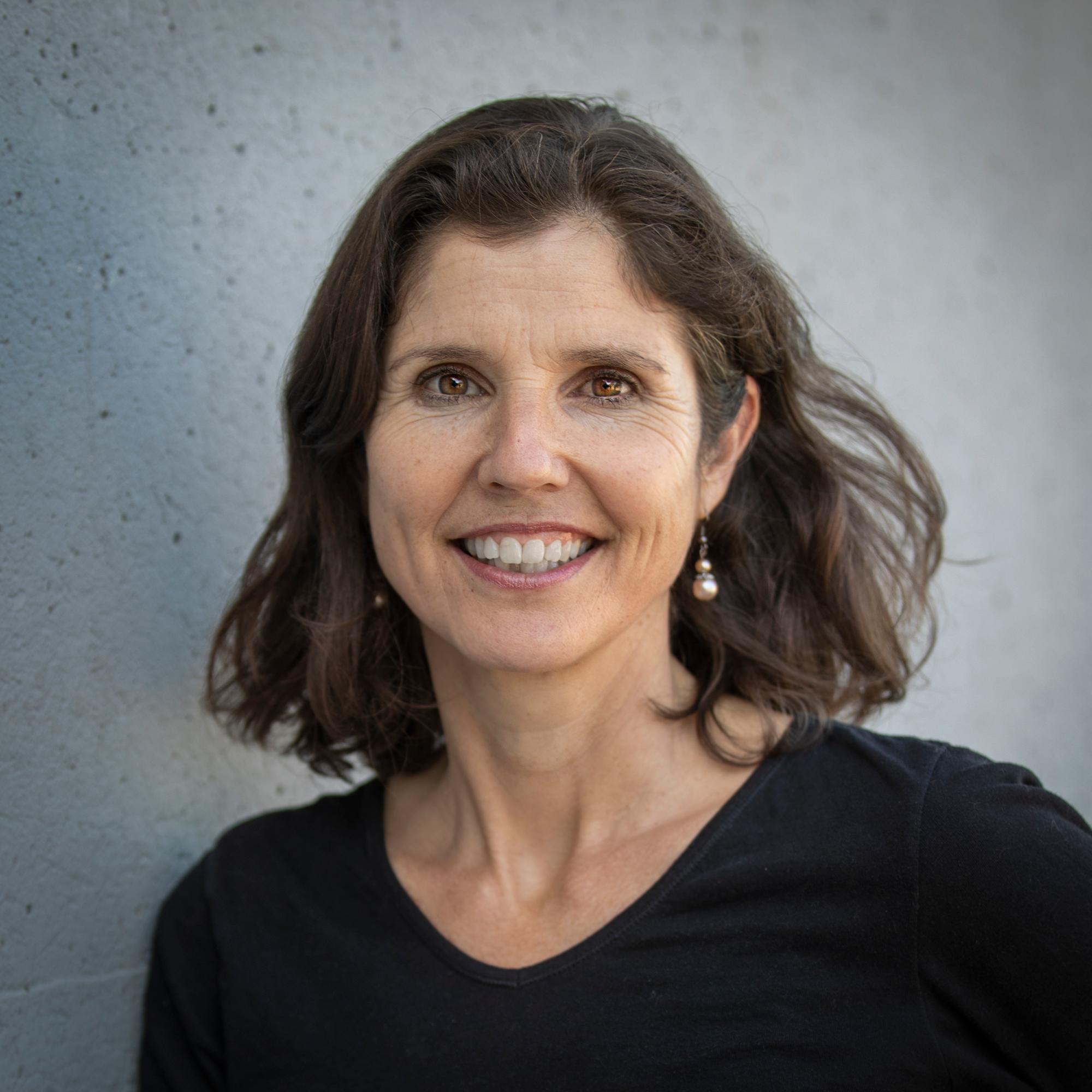 Headshot of woman with dark hair smiling in a black top.