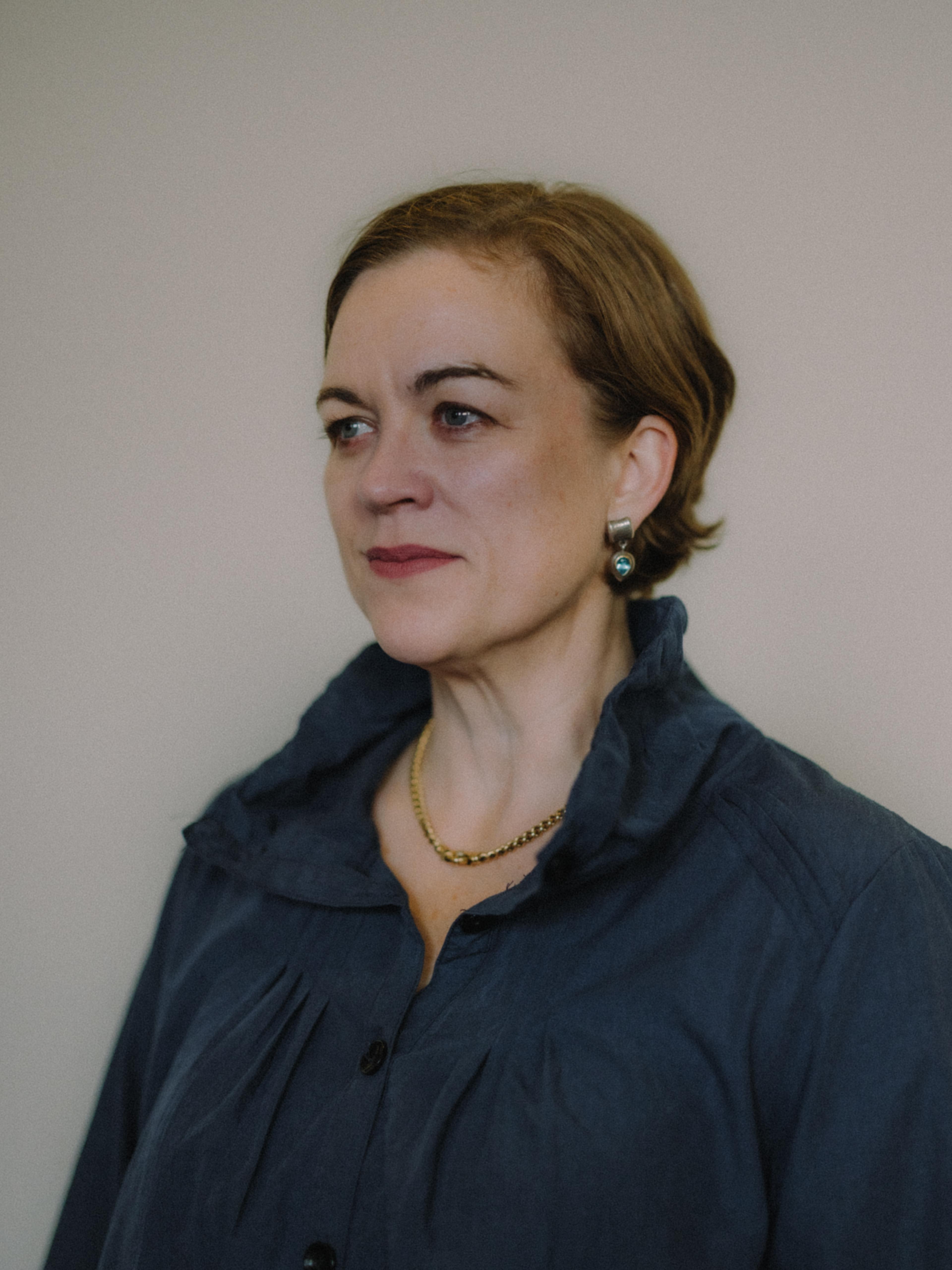 Headshot of a woman with short brown hair wearing a dark blue shirt.