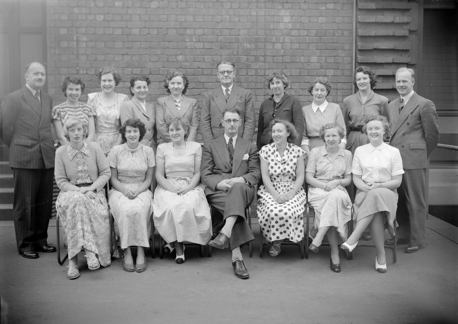 Archive photo of a group of people organised into two rows. The front row sit in front of the standing row.
