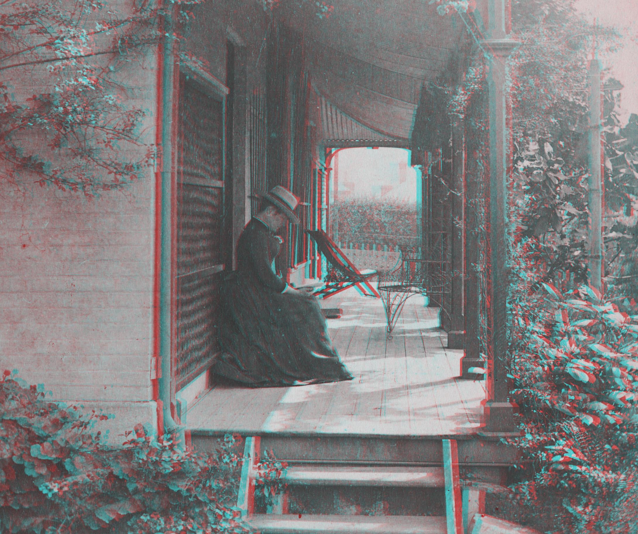 A black and white anaglyph photo of a woman in Victorian dress sitting on a porch reading a book