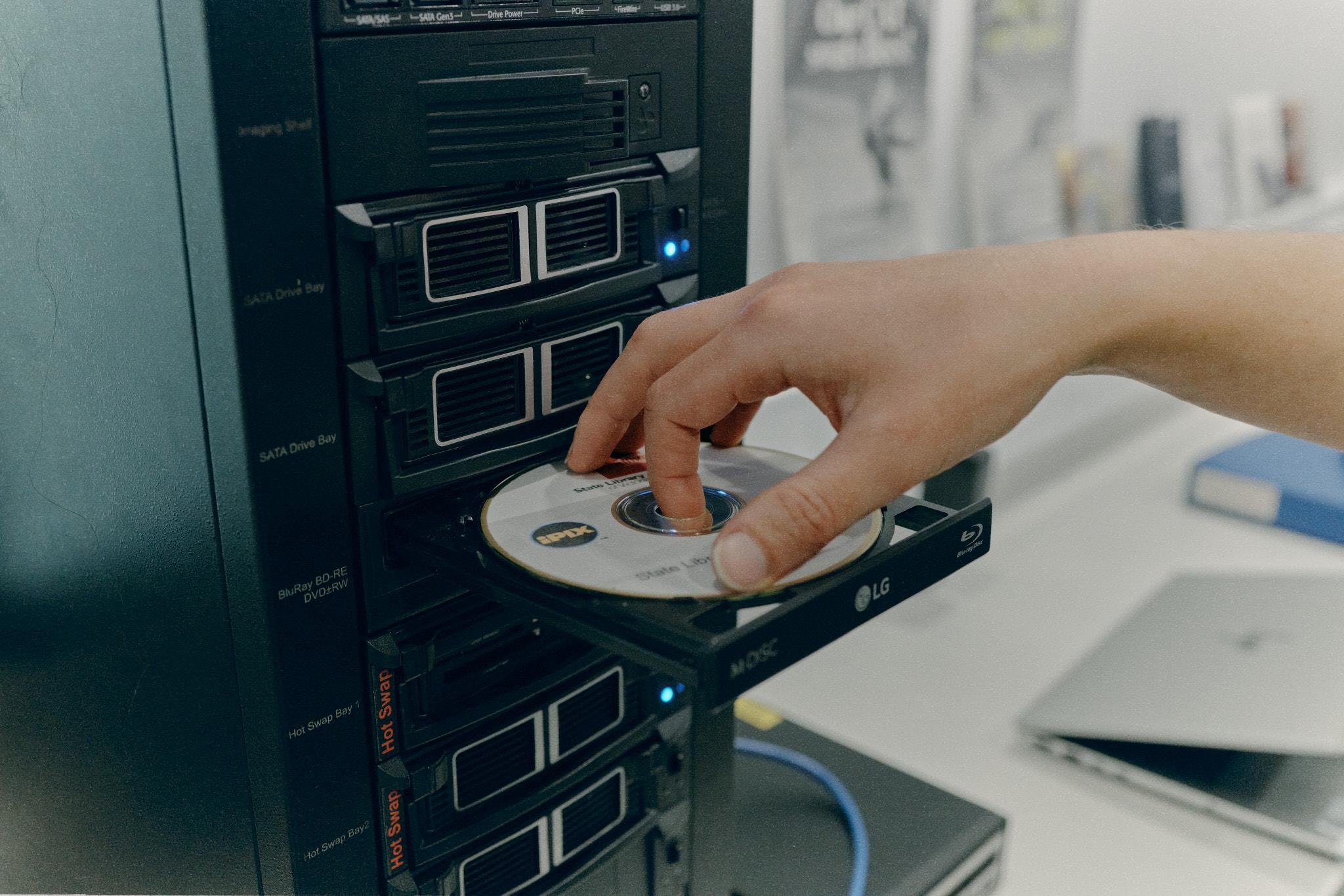 A hand loading a CD ROM in a disc drive