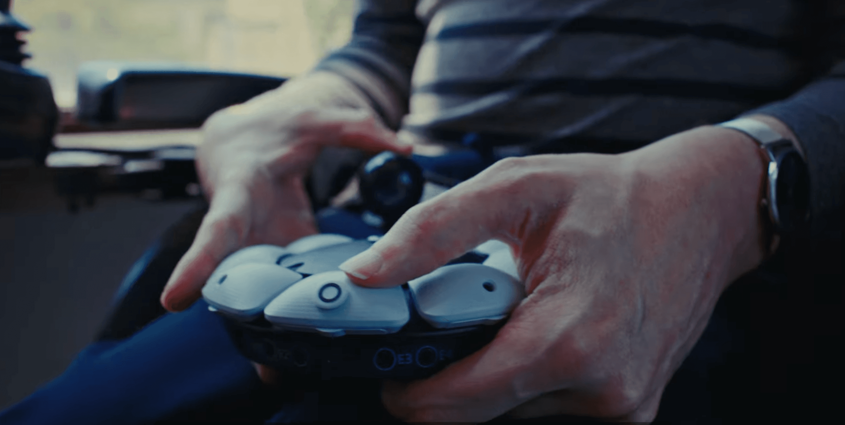 A pair of hands holding a Playstation controller specially designed to be accessibly