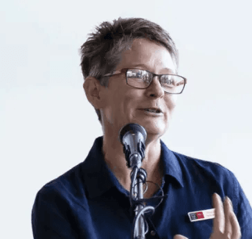 A headshot of a woman (Melanie Swalwell) with short hair and glasses delivering a lecture